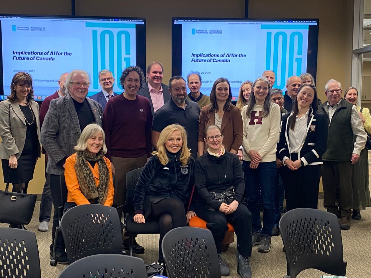 A group of people standing in front of screens reading "Implications of AI for the future of Canada"